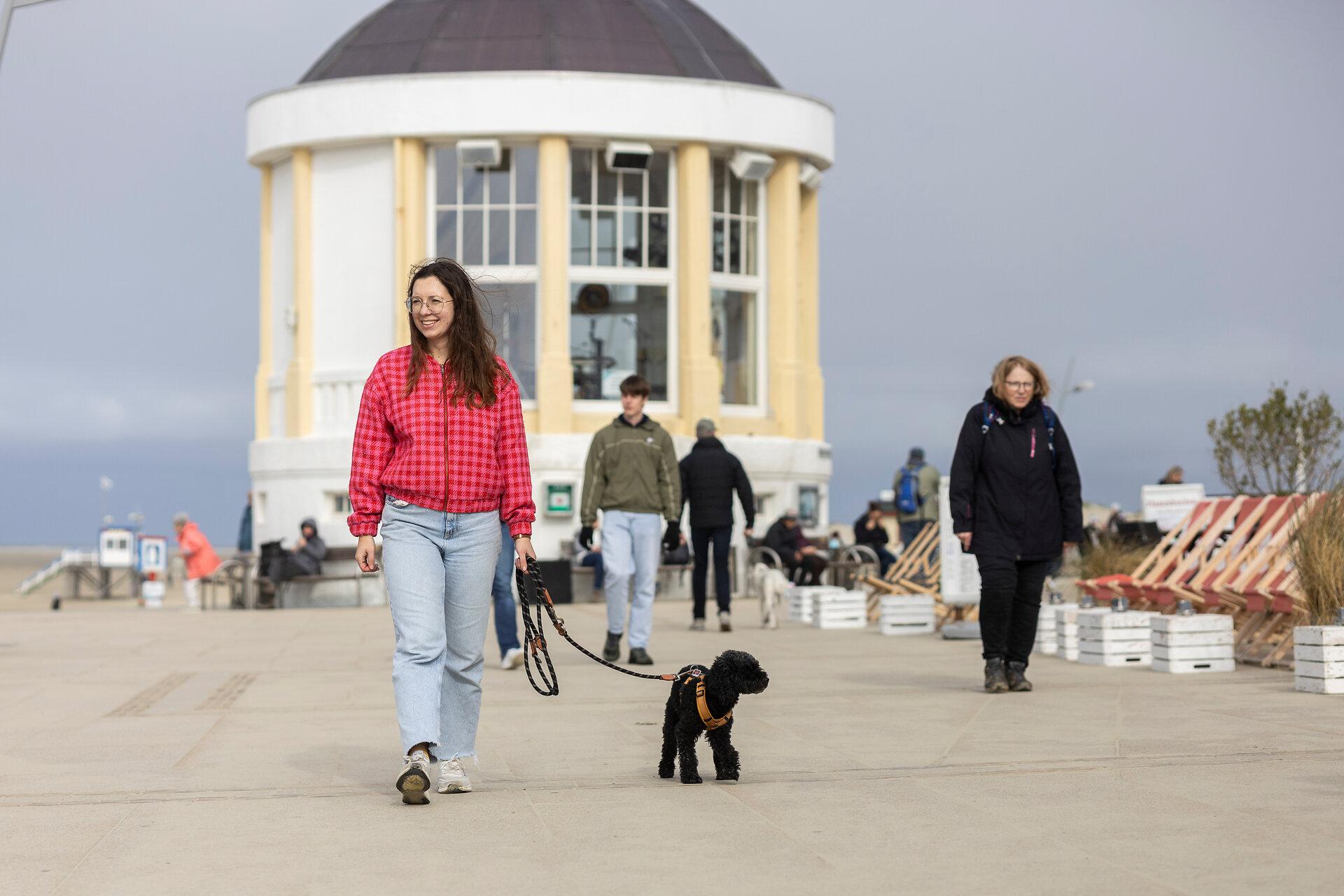 Frau mit Hund bei einem Spaziergang vor dem Musikpavillon an der Promenade auf Borkum