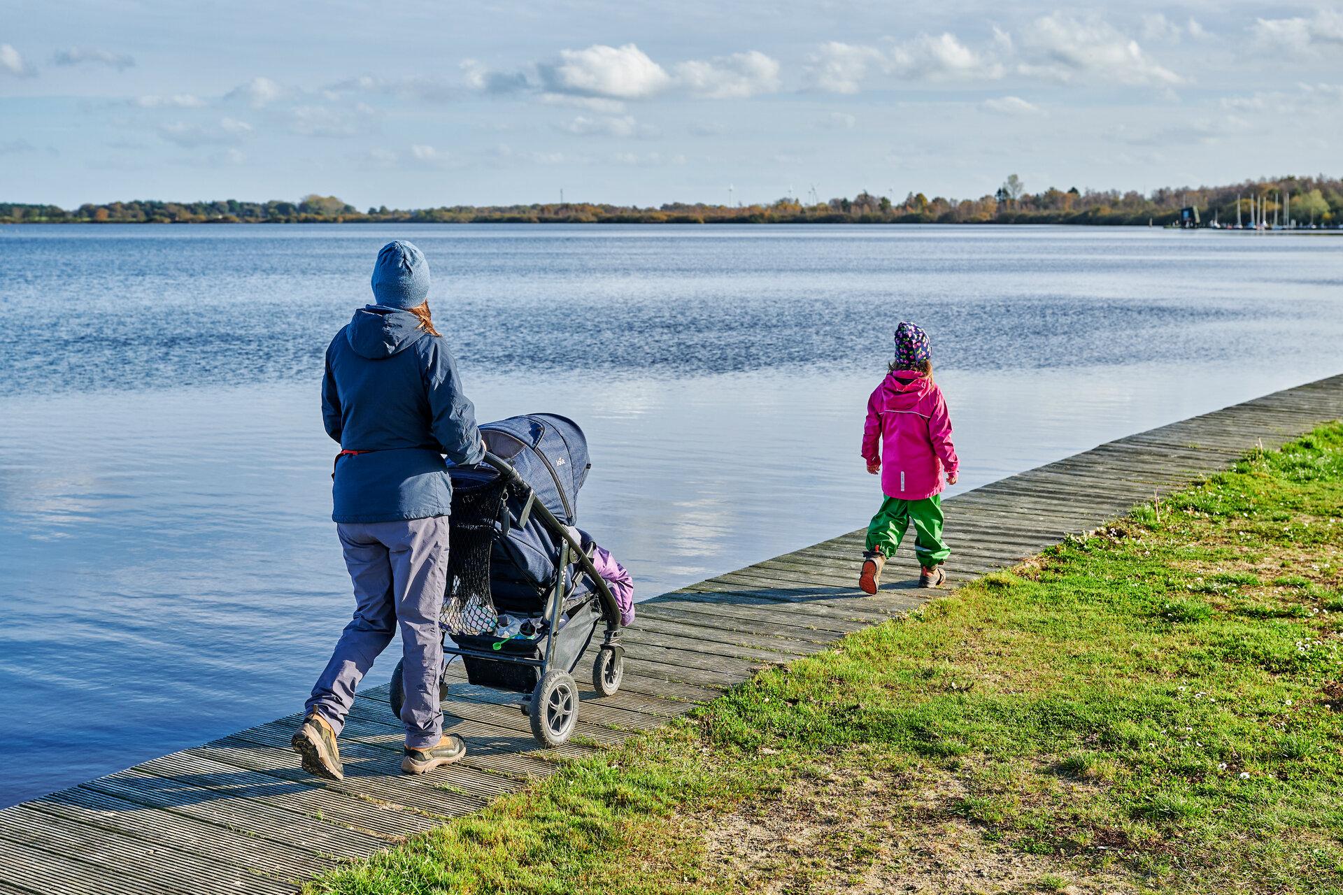 Mutter mit Kind und Kinderwagen am Seeufer in Bad Bederkesa im Herbst