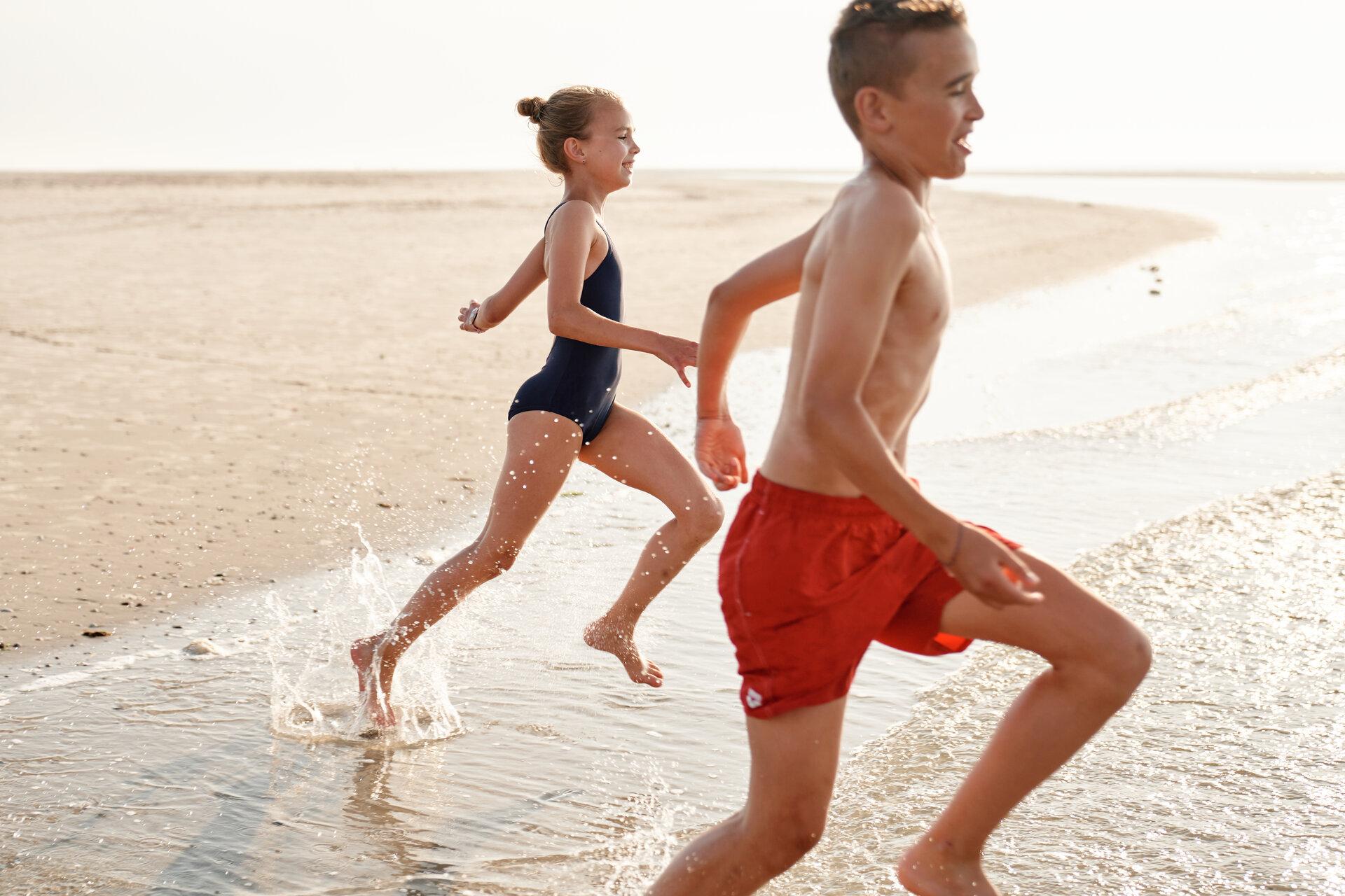 Kinder rennen ins Wasser am Strand von Spiekeroog