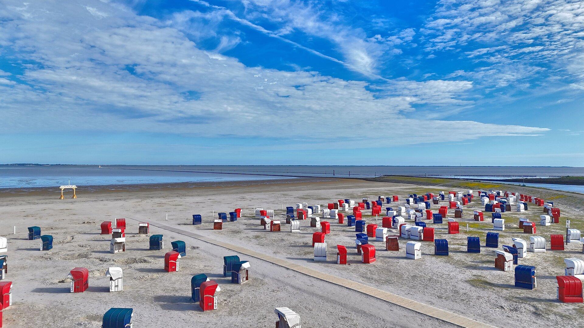 rote, blaue und weiße Strandkörbe am Strand in Bensersiel mit Meerblick 