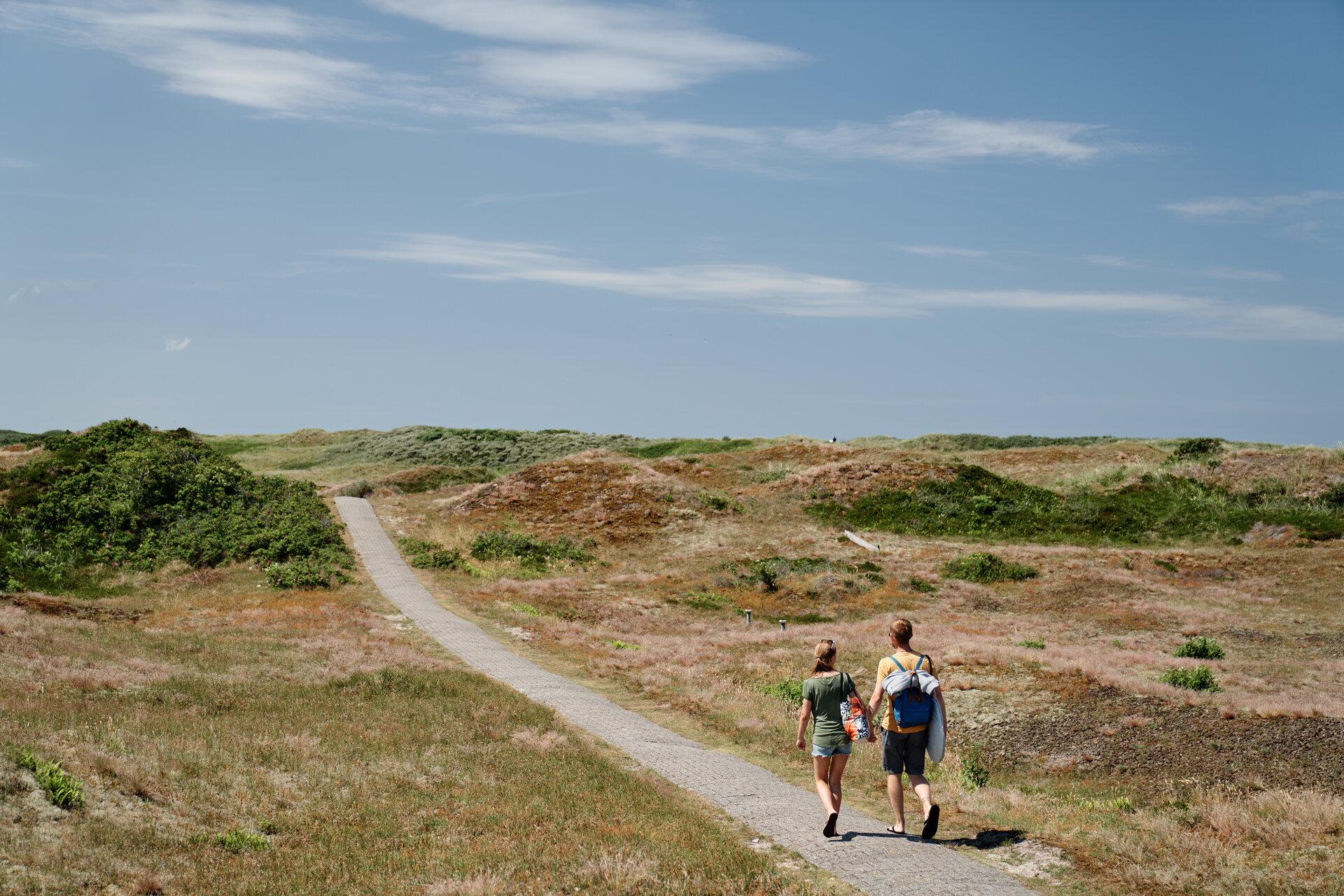 Paar spaziert entlang der Dünen auf Spiekeroog
